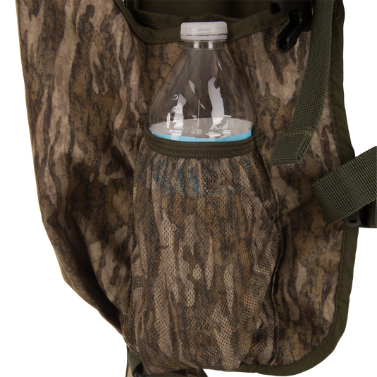 Time & Motion™ Gunslinger Turkey Vest with camouflage bag shown, featuring adjustable straps, mesh pockets for water bottle, and efficient pocket organization for hunting essentials.