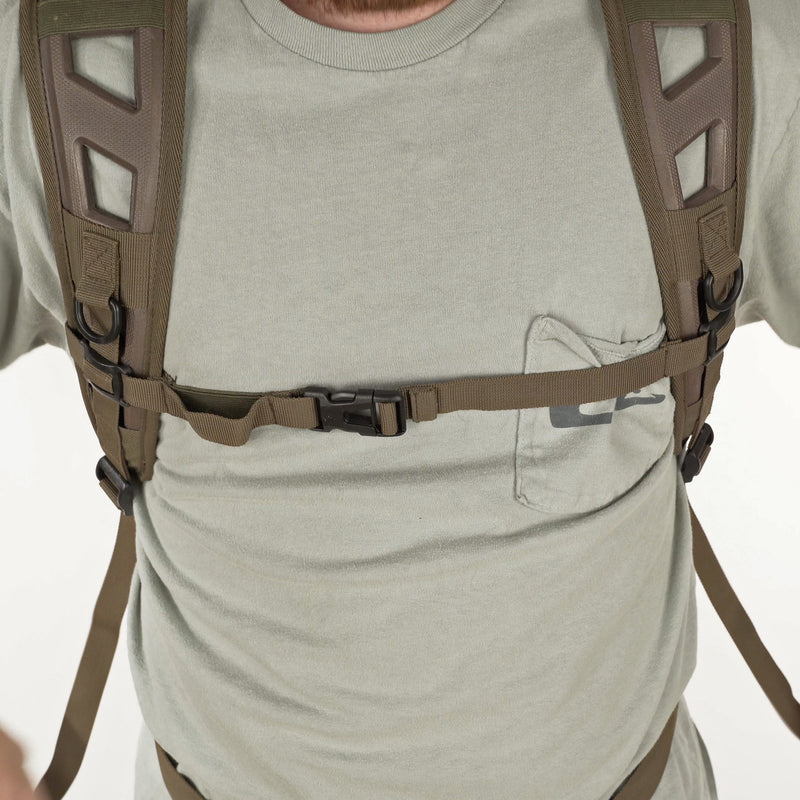 A man wearing a grey shirt and grey pants, showcasing the Camo Daypack by Purewhitelaneshop. Features include a large storage area, hydration pouch pocket, EVA shoulder straps, and more.