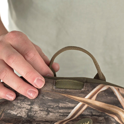 A person holding a Youth Camo Daypack, a compact design for storing essential items in both casual and hunting applications.