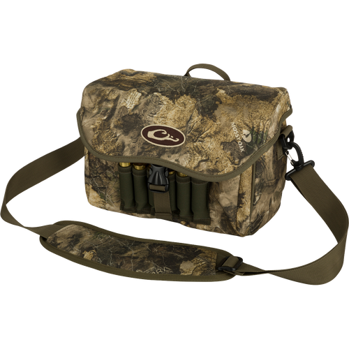 Refuge Blind Bag by Purewhitelaneshop: Camouflage bag with gun case, ammo, and logo. Adjustable strap, durable hardware, outer pocket, shell loops, and waterproof lining. Ideal for daily waterfowl hunting.