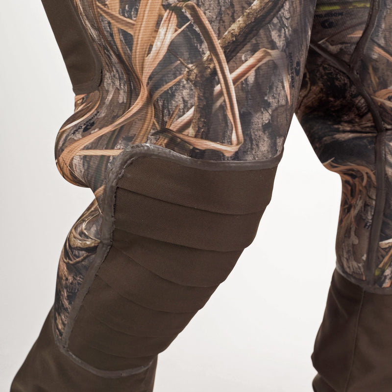 A person wearing camouflage pants and a brown jacket, showcasing the Buckshot Eqwader 1600 Neoprene Wader 3.0.