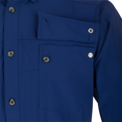 A close-up of the Performance Mesh Paneled Short Sleeve Shirt, featuring a blue fabric with button-through flap chest pockets and a hidden button-down collar. The shirt has laser-punched mesh back panels for increased ventilation and offers UPF 50 sun protection, moisture-wicking, and quick-drying properties. Perfect for outdoor activities.