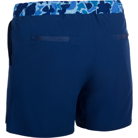 A versatile pair of blue shorts with a built-in liner, perfect for the playground or beach. Made with quick-drying, moisture-wicking fabric and a 4-way stretch for comfort. Features include scalloped hem, adjustable drawstring waistband, and multiple pockets. Youth Commando Lined Volley Short 5 from Purewhitelaneshop.