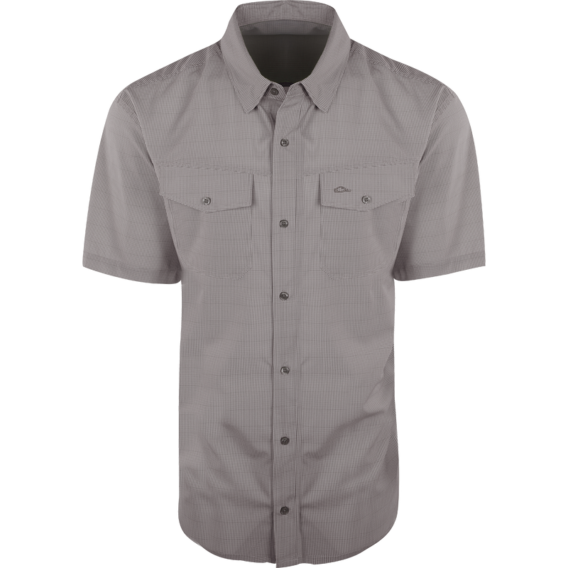 A close-up of the Traveler's Check Shirt S/S, a lightweight and breathable shirt with four-way stretch for freedom of movement. Features moisture-wicking fabric and two chest pockets with button flaps. Ideal for the man on the go.