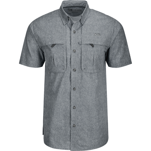 A grey Heritage Heather Shirt with pockets, made of 100% polyester micro mesh for natural cooling and quick drying. Features include a hidden button-down collar, vented cape back, and two front chest pockets. Perfect for performance and comfort in any setting.