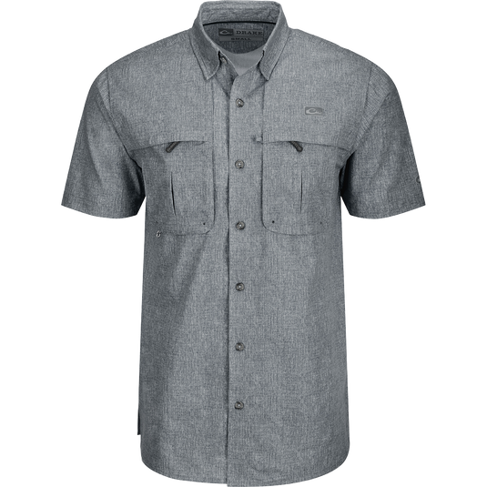 A grey Heritage Heather Shirt with pockets, made of 100% polyester micro mesh for natural cooling and quick drying. Features include a hidden button-down collar, vented cape back, and two front chest pockets. Perfect for performance and comfort in any setting.