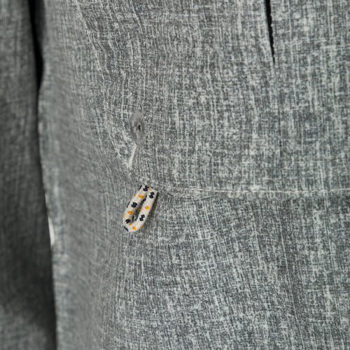 Heritage Heather Shirt L/S - Close-up of jacket button, rope, and grey object. Performance shirt with micro mesh, UPF30, moisture-wicking, and quick-drying fabric. Features hidden button-down collar, vented cape back, chest pockets, and roll-up sleeves. Ideal for hunting, fishing, and outdoor activities.