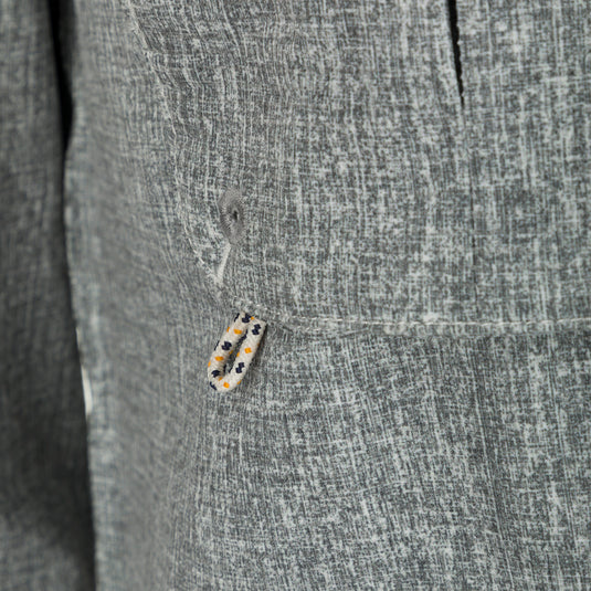 Heritage Heather Shirt L/S - Close-up of jacket button, rope, and grey object. Performance shirt with micro mesh, UPF30, moisture-wicking, and quick-drying fabric. Features hidden button-down collar, vented cape back, chest pockets, and roll-up sleeves. Ideal for hunting, fishing, and outdoor activities.