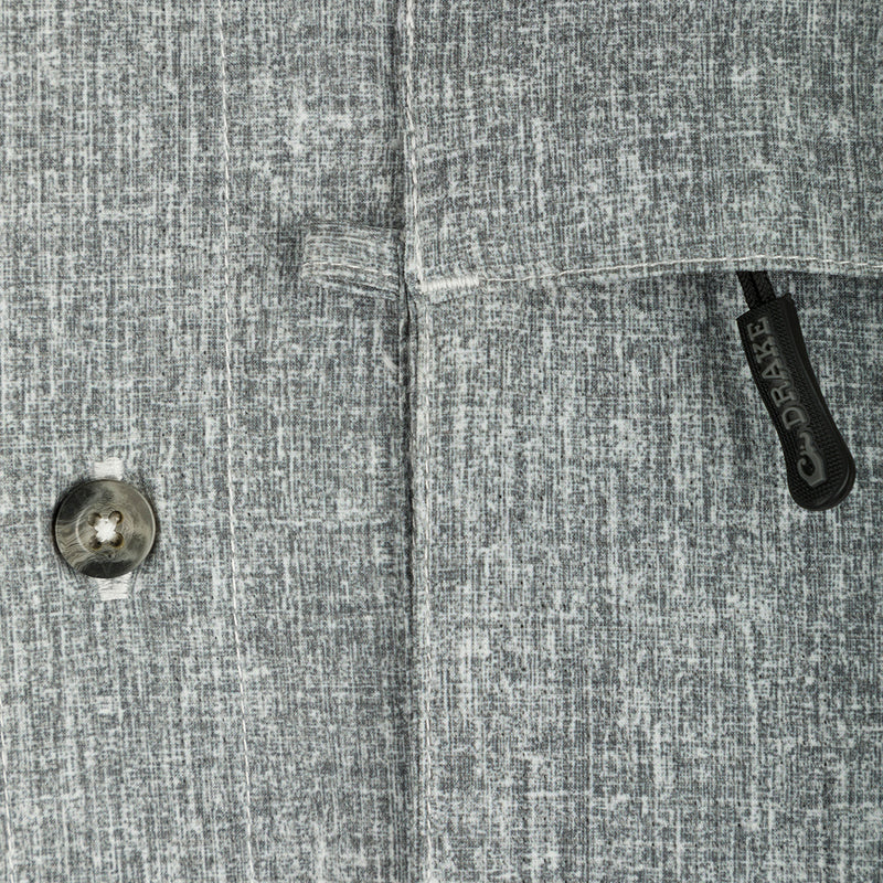 Heritage Heather Shirt L/S: A close-up of a button on a grey patterned shirt made of lightweight, moisture-wicking polyester fabric with UPF30 sun protection.