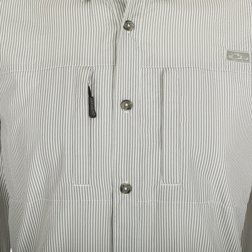 A close-up of the Drake Classic Seersucker Stripe Shirt, featuring a button-down collar, hidden zippered chest pocket, and Magnattach™ closure. Made from 72% Polyester and 28% Nylon, this soft and featherweight shirt offers UPF30 sun protection and moisture-wicking properties. With a vented cape back and split tail hem, it provides comfort and versatility. Perfect for big game hunting, waterfowl hunting, turkey hunting, and fishing.