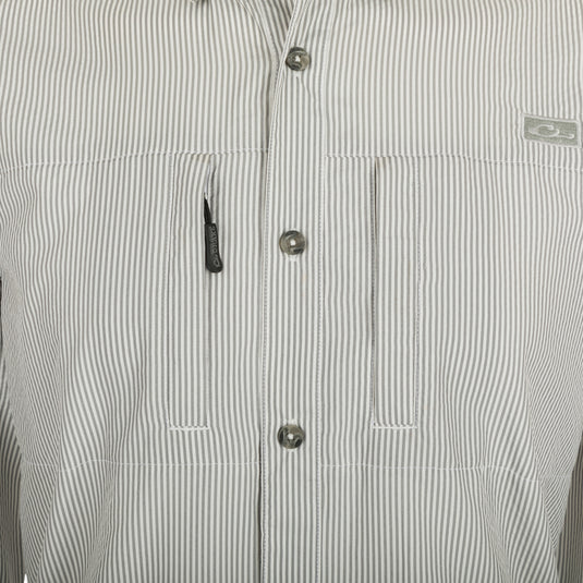 A close-up of the Drake Classic Seersucker Stripe Shirt, featuring a button-down collar, hidden zippered chest pocket, and Magnattach™ closure. Made from 72% Polyester and 28% Nylon, this soft and featherweight shirt offers UPF30 sun protection and moisture-wicking properties. With a vented cape back and split tail hem, it provides comfort and versatility. Perfect for big game hunting, waterfowl hunting, turkey hunting, and fishing.