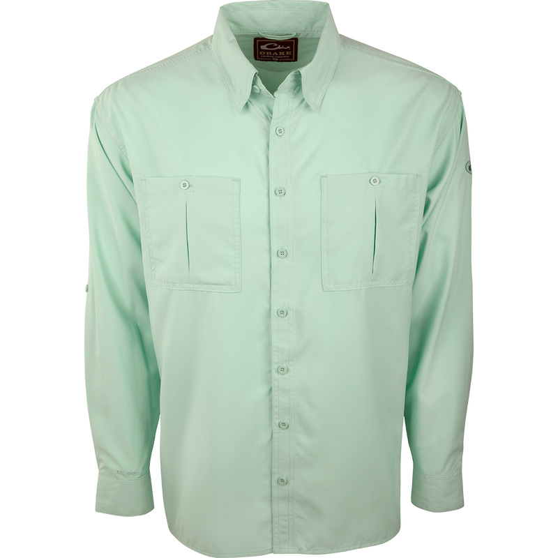 A close-up of the Flyweight Shirt with Vented Back L/S. A green button-up shirt made of ultra-lightweight polyester. Features include Sol-Shield™ UPF 50+ sun protection, vented mesh back, and horizontal chest pockets. Quick-drying, moisture-wicking, and breathable.