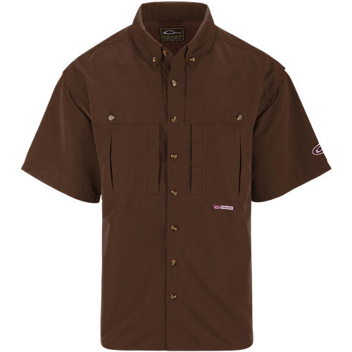 A brown short sleeved shirt with a logo on the chest, perfect for outdoor activities. Features include front and back ventilation, oversized chest pockets, and a zippered pocket. Made with wrinkle-resistant EasyCare™ fabric and a poly-mesh lining for breathability. From Purewhitelaneshop, known for high-quality hunting gear and clothing.