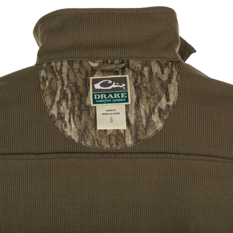 MST Windproof Softshell Vest - A close-up of the jacket with a label and logo. Expert-level functionality with secure storage pockets and customizable fit. Superior comfort and breathability with 4-Way Stretch and Grid-Fleece Collar Lining.