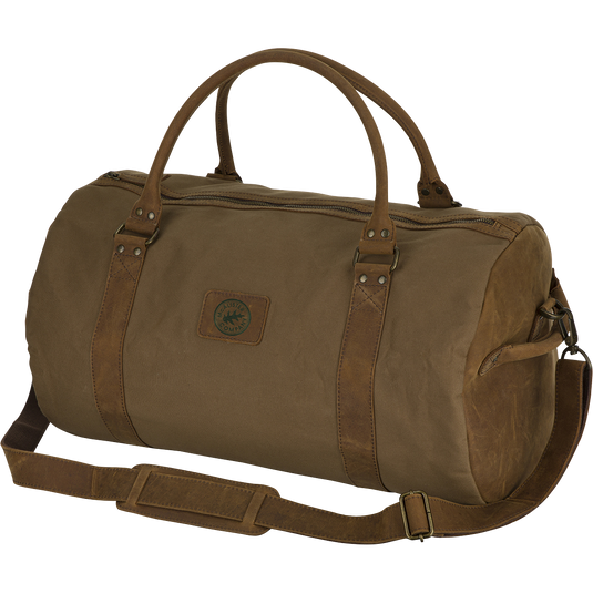 McAlister Leather & Waxed Canvas Duffel Bag: A rugged brown bag with straps, made of top grain water buffalo leather and premium waxed cotton fabric. Features brass hardware, leather shoulder strap, rolled handles, and a 40L capacity. Perfect for hunting gear and outdoor adventures.