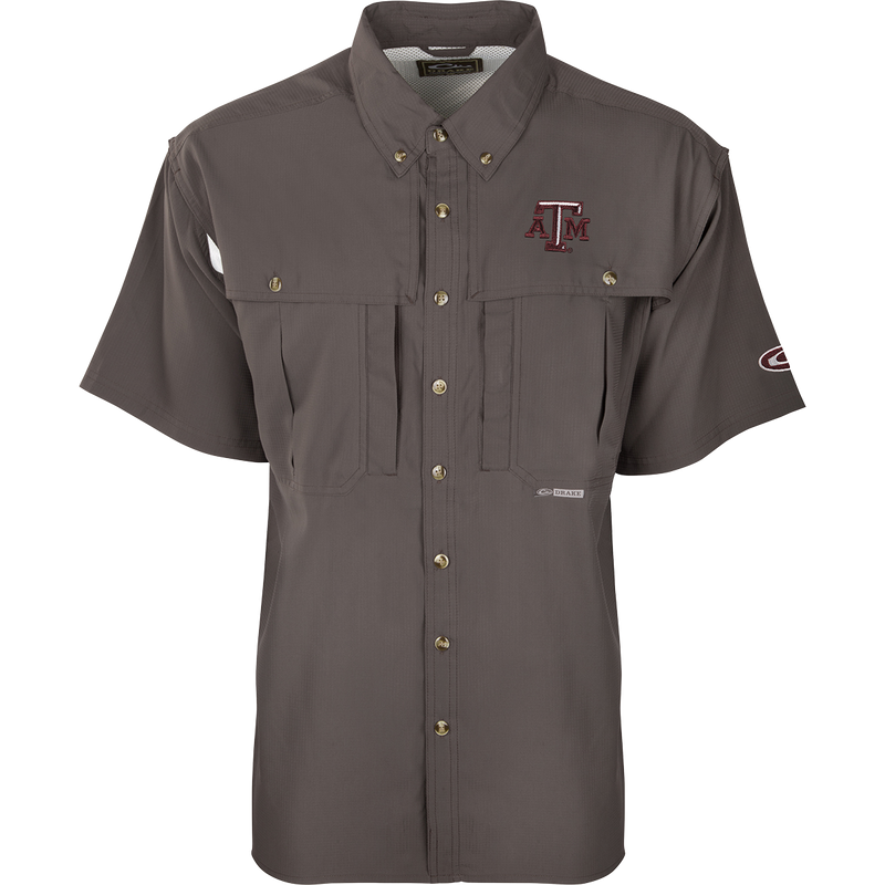 Texas A&M S/S Flyweight Wingshooter: A grey shirt with a logo, designed for warm-weather outdoor activities. Made of ultra-lightweight polyester fabric that dries quickly and wicks moisture away. Features include UPF 50+ sun protection, vented back, chest pocket, and zipper pocket.