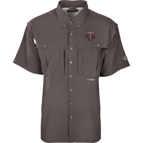 Texas A&M S/S Flyweight Wingshooter: A grey shirt with a logo, designed for warm-weather outdoor activities. Made of ultra-lightweight polyester fabric that dries quickly and wicks moisture away. Features include UPF 50+ sun protection, vented back, chest pocket, and zipper pocket.