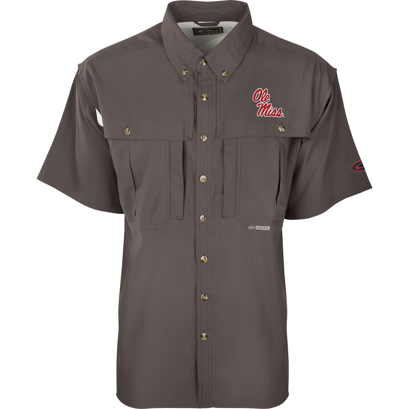 A close-up of the Ole Miss S/S Flyweight Wingshooter shirt, featuring a logo on a grey background. Made with ultra-lightweight polyester, it offers quick-drying, moisture-wicking, and breathable properties. Includes Sol-Shield™ UPF 50+ sun protection, Magnattach™ vertical chest pocket, and a vertical zipper pocket. Ideal for warm-weather outdoor activities.